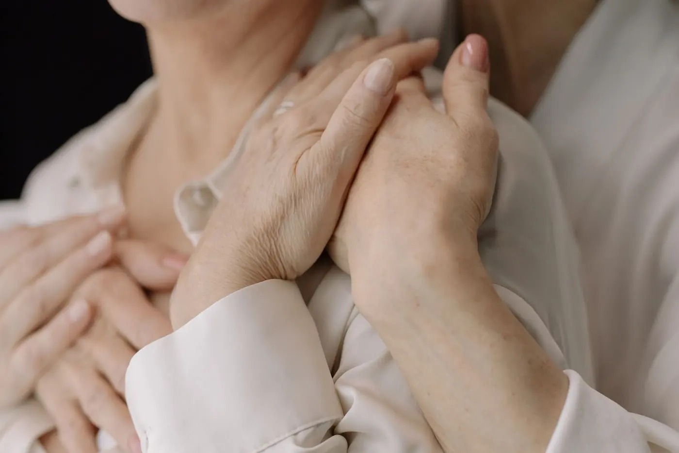 A carer's hands gently holding another person's hands